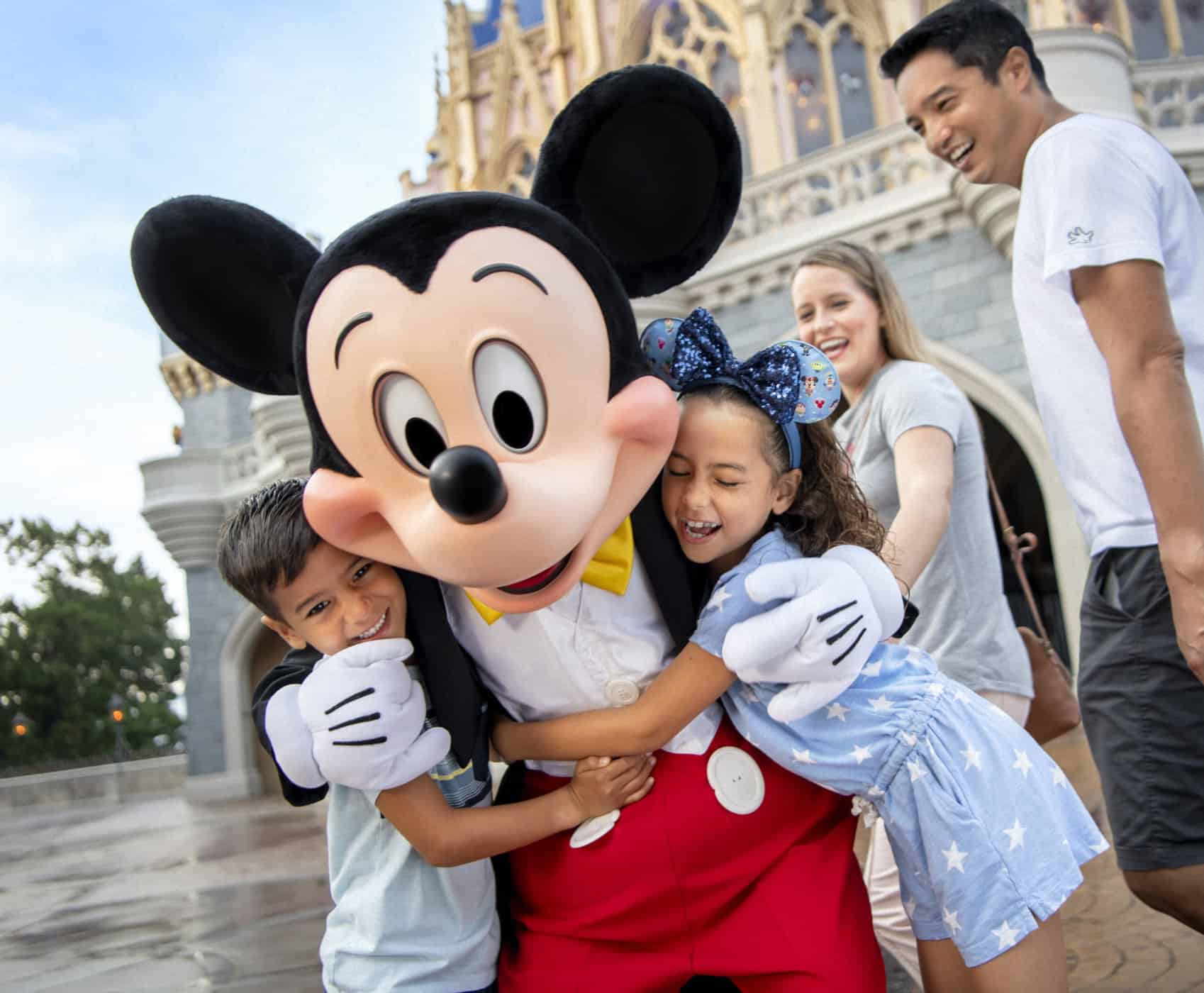 Kids hugging Mickey Mouse character during a family Disney vacation