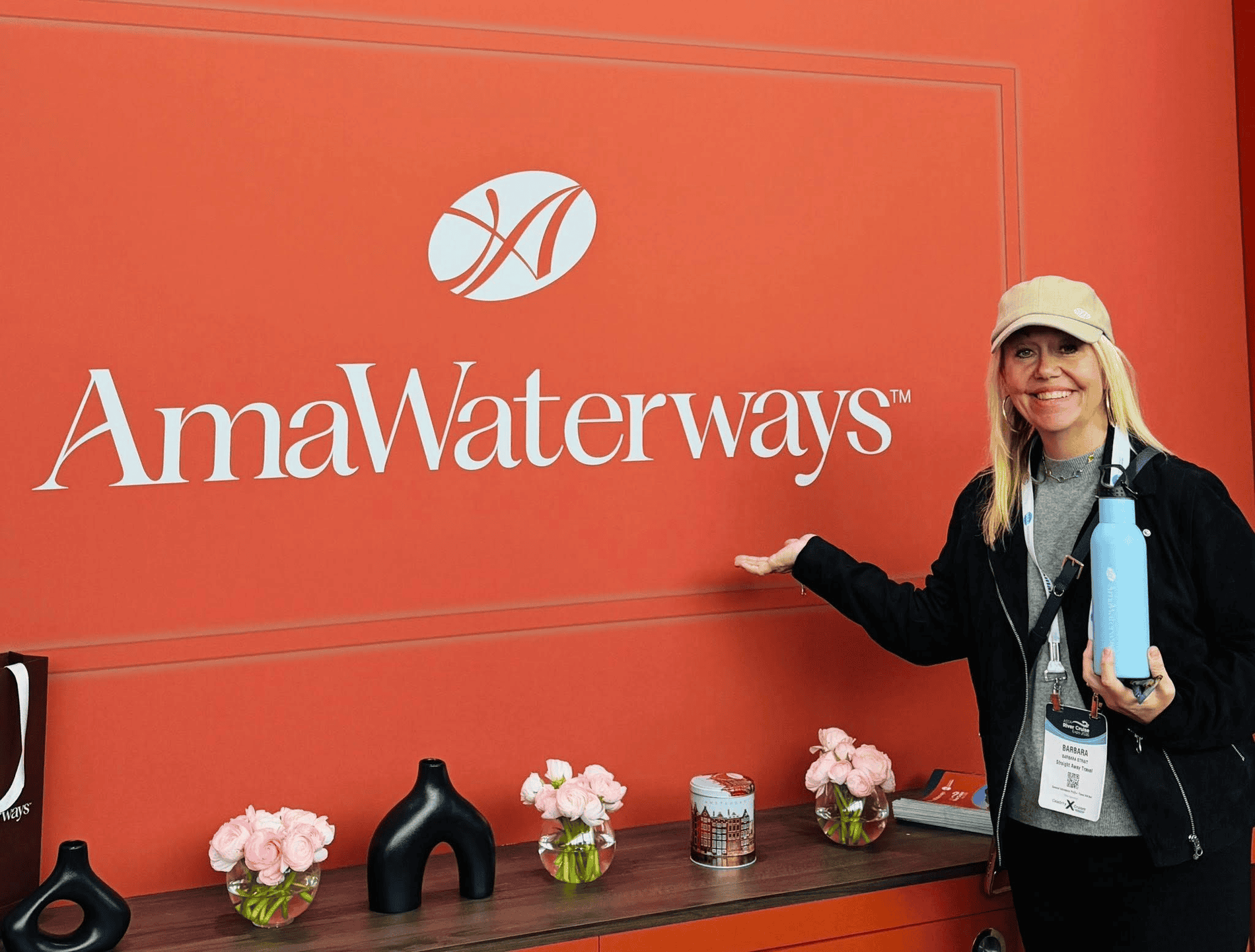 Barb the CEO of Straight Away Travel standing beside the Amawaterways sign